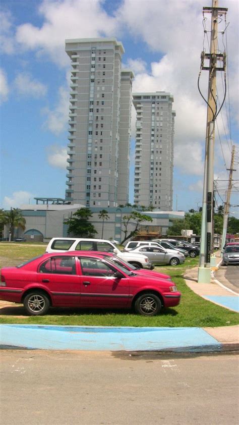 Two Cars Parked On The Grass In Front Of Tall Buildings