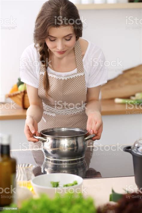 Young Brunette Woman Cooking Soup In Kitchen Housewife Holding Wooden Spoon In Her Hand Food And