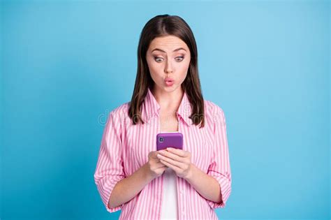 photo portrait of amazed woman holding phone in two hands isolated on pastel blue colored