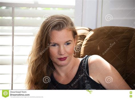 Closeup Portrait Mature Blonde Female Sitting On Sofa Looking Away From Camera Stock Image