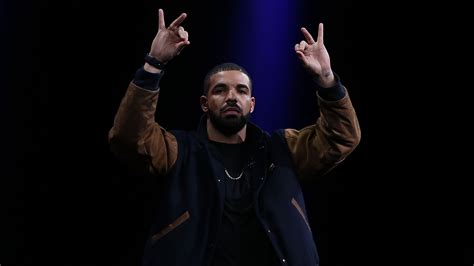 Drake Is Showing Hand Sign Wearing Brown Black Overcoat In Black