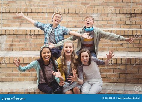 Portrait Of Smiling School Students Sitting On Staircase Having Fun In