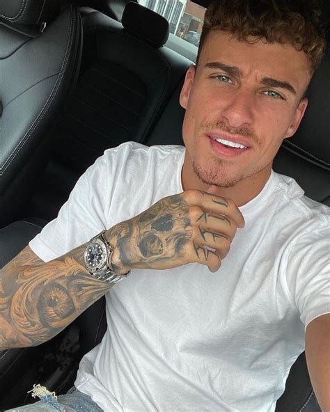A Man Sitting In The Back Seat Of A Car With Tattoos On His Arm And Wrist