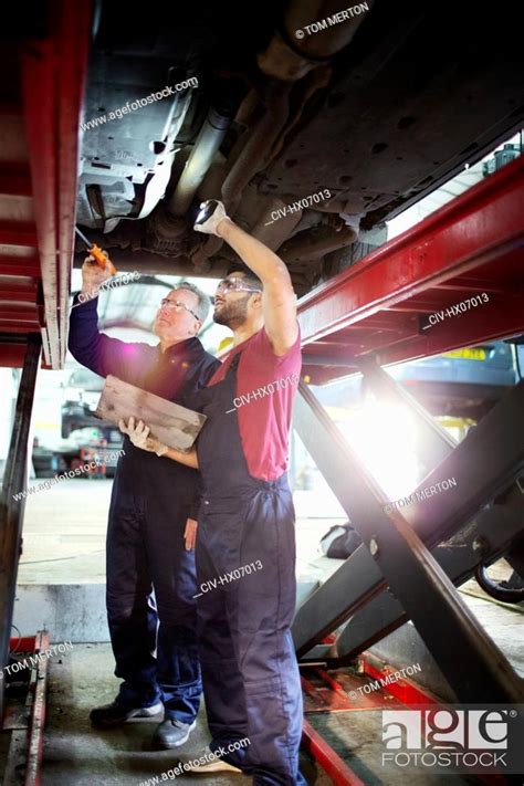 Male Mechanics Working Under Car In Auto Repair Shop Stock Photo