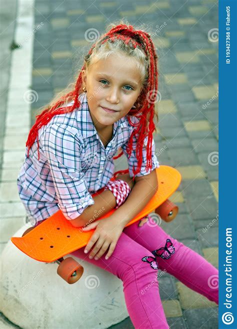 Portrait Of A Stylish Little Girl With A Skateboard Stock Photo