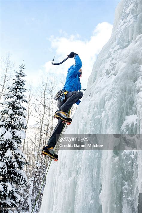 Climber Using Ice Axe To Climb A Frozen Waterfall High Res Stock Photo