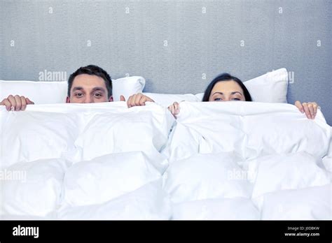 Happy Couple Hiding Under Blanket In Bed Stock Photo Alamy