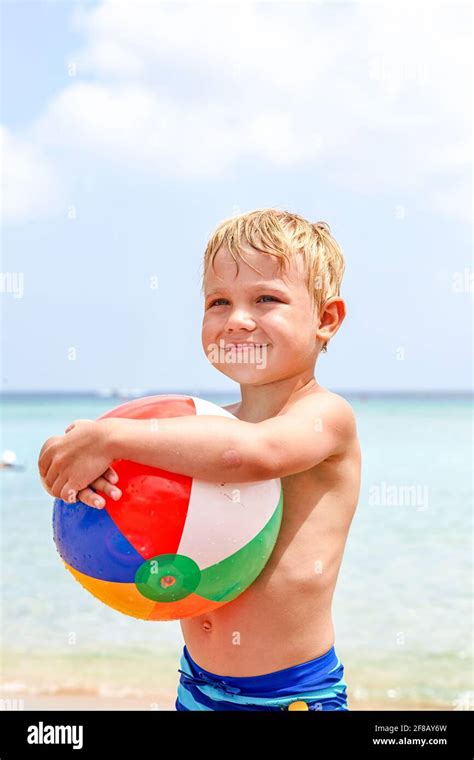 Excited Laughing Boy Holding Colorful Beach Ball At The Beach Enjoying