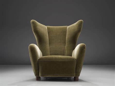 Liven up your surroundings with a wonderfully comfortable armchair designed in a classic wingback form with a high back and pleasantly curved armrests. Danish Green Velvet Wingback Chair For Sale at 1stdibs