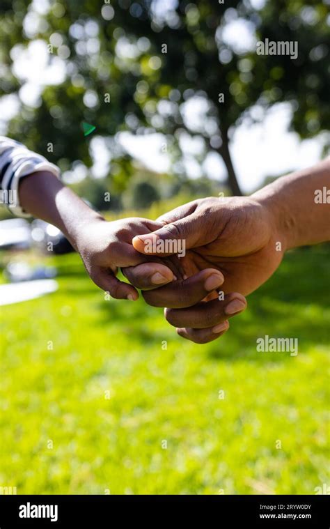 Closeup Of African American Father And Son Holding Hands Over Grassy