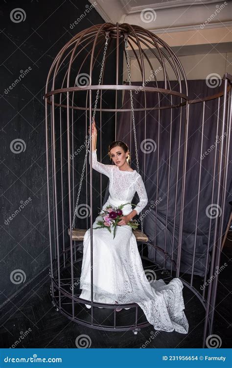 Fashion Bride Sits On Swing In An Iron Cage Peeking Out From Behind The Bars Fictitious
