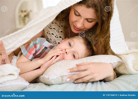 Mom Gently Looks At Her Son They Lying On Bed Covered With Bedspread In Bright Bedroom Stock