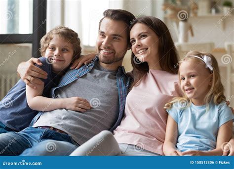 Happy Parents Sitting With Smiling Children Siblings At Comfortable
