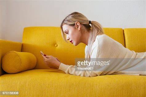 Blonde Woman Lying On Sofa Using Smartphone At Home Photo Getty Images
