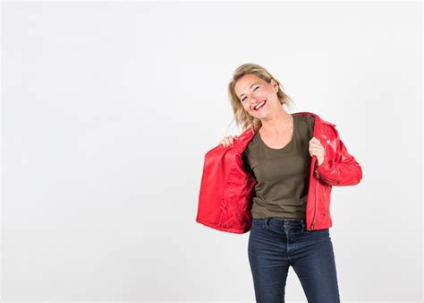 Porträt Der Blonden Reifen Frau In Der Roten Lederjacke Die Gegen Weißen Hintergrund Steht