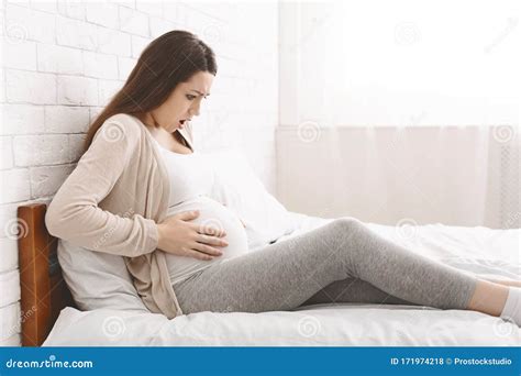 Pregnant Woman Suffering From Abdominal Pain At Home Stock Photo
