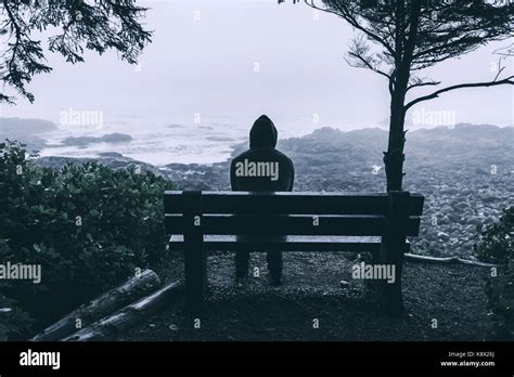 Sad And Lonely Man Sitting On Bench Overlooking Sea On Vancouver Stock