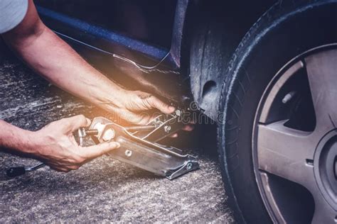 Man Lifting Car With Jack For Tire Changing Of Punctured Wheel Tire Change Oncept Stock Photo