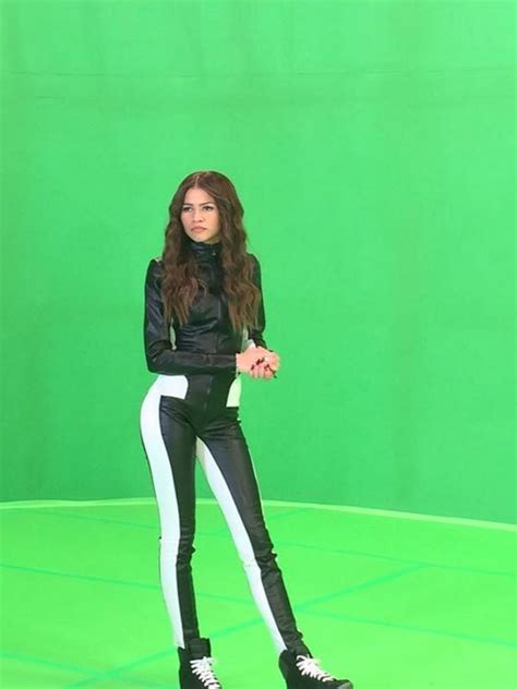 A Woman Standing In Front Of A Green Screen With Her Hands On Her Hips
