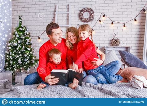Feliz Familia Leyendo Un Libro En Casa En Navidad Foto De Archivo
