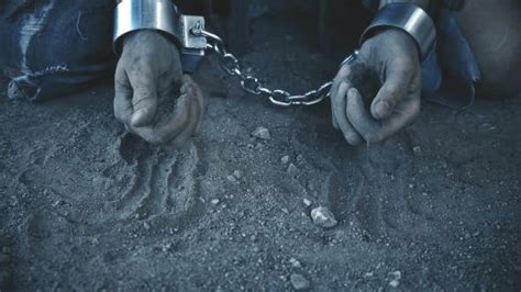 A Prisoner In Chains On His Knees Touching The Dusty Ground Stock Footage