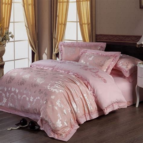 A Bed With Pink Comforters And Pillows In A Room Next To A Window