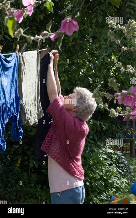 Old Lady Hanging Clothes On The Washing Line To Dry On A Summers Day