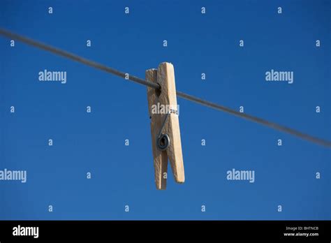 Single Clothes Peg Hanging On A Washing Line Against A Bright Blue Sky