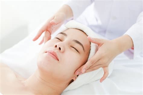 mulher jovem asiática recebendo tratamento de spa no salão de beleza massagem de rosto spa