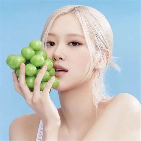 A Woman Holding Green Fruit In Front Of Her Face