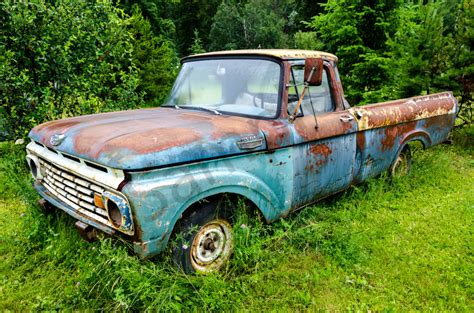 Blue rusting Ford classic pickup truck in field, art photograph