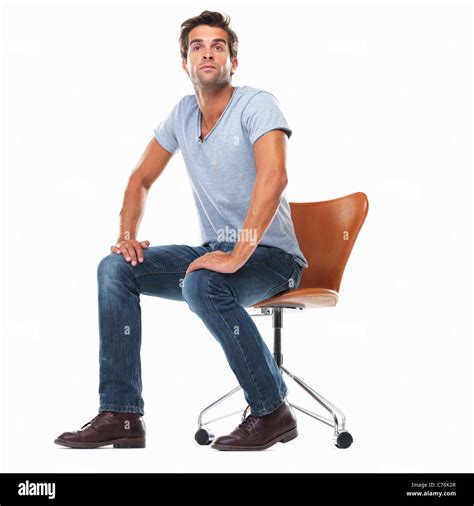 Studio Shot Of Young Man Sitting On Chair With Hands On Laps Stock