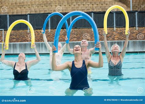 Happy Trainer And Senior Swimmers Exercising In Swimming Pool Stock