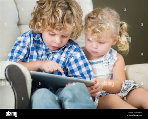 Adorable Young Brother And Sister Using Their Computer Tablet Together