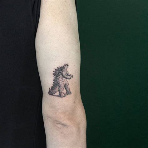 Mini Godzilla Tattoo On The Back Of The Right Arm