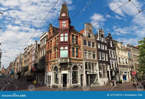 Typical Street With Old Traditional Houses In Amsterdam Under Blue Sky