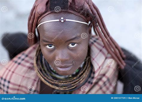 Portrait Of A Himba Girl Looking After The Goat Herd Carrying A Baby On