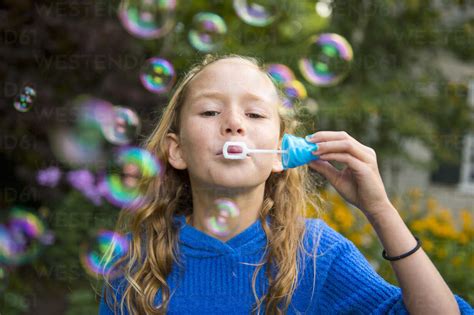 Girl Blowing Bubbles In Garden Stock Photo