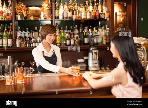 Female Bartender Serving Drink To Woman At Bar Counter Stock Photo Alamy