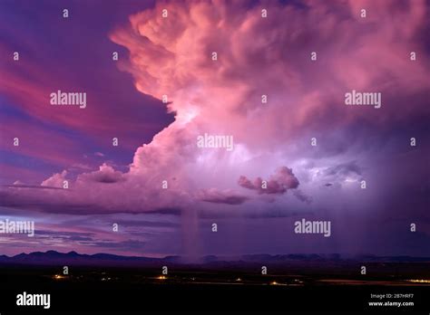 A Thunderstorm Cumulonimbus Cloud Illuminated By Lightning At Sunset