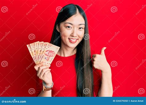 Young Chinese Woman Holding Mexican Pesos Smiling Happy And Positive