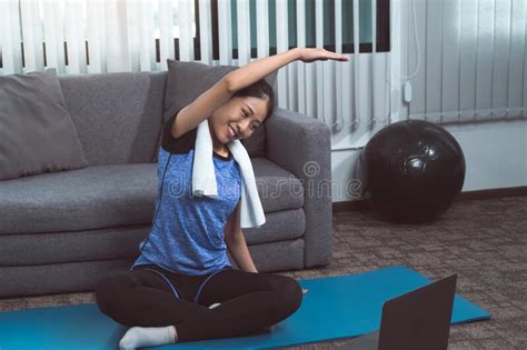 Asian Woman Stretching During A Yoga Class With A Trainer At Her Laptop Computer At Home Stock