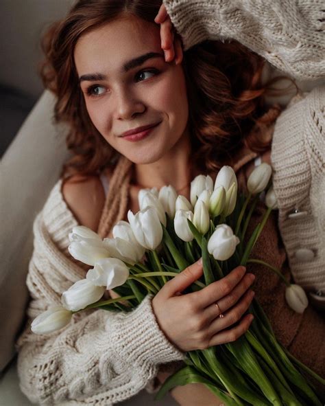 A Woman Is Holding Some White Flowers In Her Hands And Smiling At The