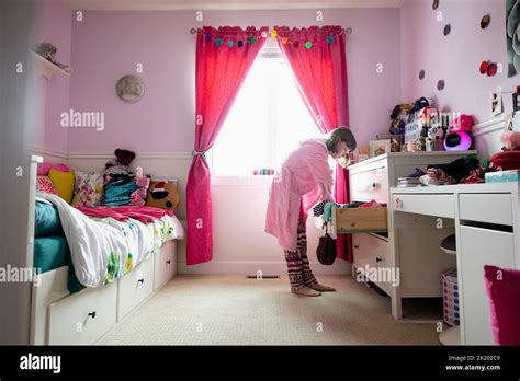 Girl Putting Clothes Away In Bedroom Stock Photo Alamy