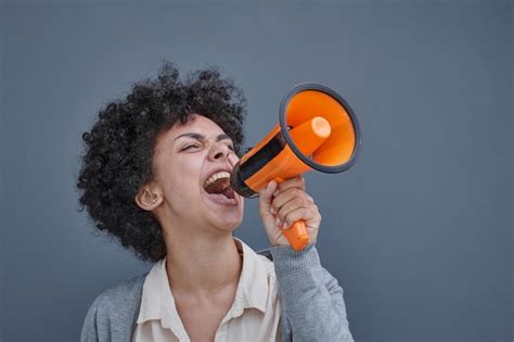 Premium Photo A Girl On A Gray Background Holds A Loudspeaker In Her