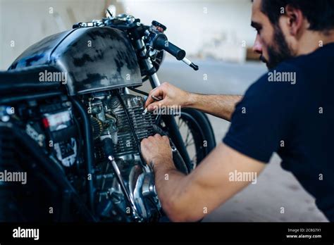 Young Male Motorcyclist Repairing Vintage Motorcycle Outdoors Stock