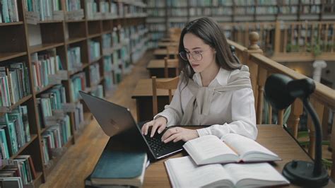 Student Doing Research In University Library With Books And Laptop