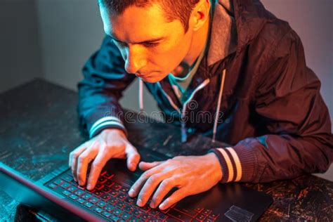 A Male Hacker Is Typing On A Laptop Keyboard In A Dark Room Under A