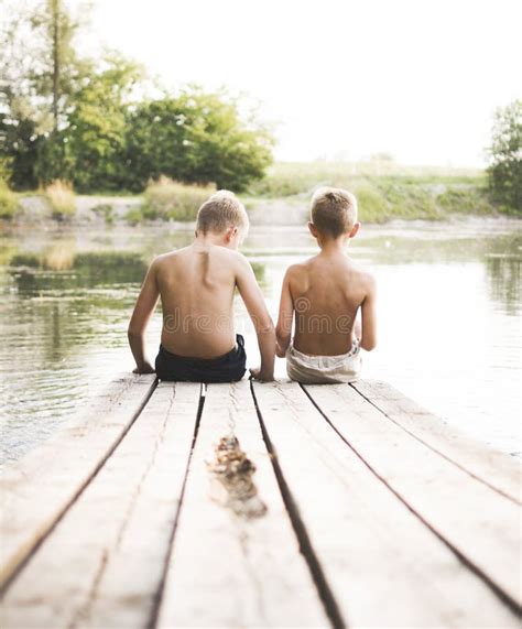 Two Boys Sitting On A Pier Stock Image Image Of Reflection 43595069