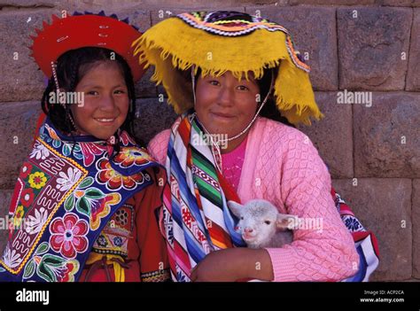 Two Indian Girls Holding A Lamb In Front Of Ancient Inca Stone Wall